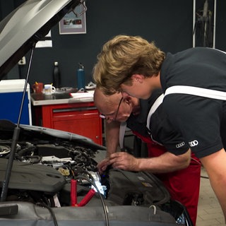 Zwei Personen untersuchen einen Automotor