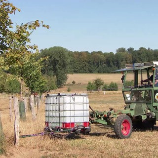 Ein Traktor beladen mit einem Wassertank auf einer Weide
