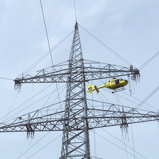 Ein Helikopter arbeitet an einem neuen Strommasten.