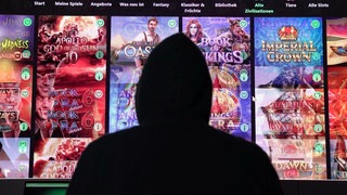 Anonymer Spielsüchtiger sitzt vor einem großen Monitor