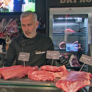 Metzger vor einer Theke mit verschiedenen Fleischsorten