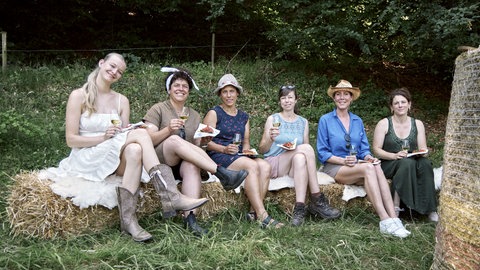 Die sechs Landfrauen der 18. Staffel sitzen in der Natur und lachen in die Kamera