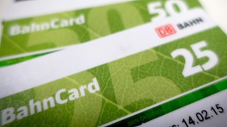 Auf einem Tisch liegen übereinander eine Bahncard 25, eine Bahncard 50 und eine Bahncard 100.