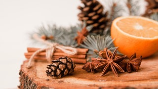 Weihnachtsgewürze, Tannenzapfen und Orangen auf hölzernem Hintergrund.