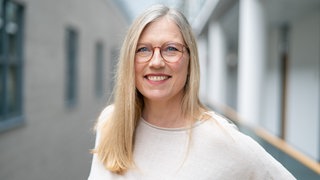 Eine Frau mit blonden Haaren lacht in die Kamera. Tina Bonin arbeitet als Autorin und Redakteurin ARD Room Tour in Mainz.
