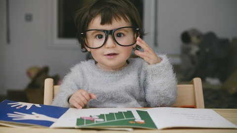 Kind mit großer Lesebrille: Einige Grundschulen nehmen spielendes Lernen und die Fragen und Themen der Kinder mehr in den Unterricht auf